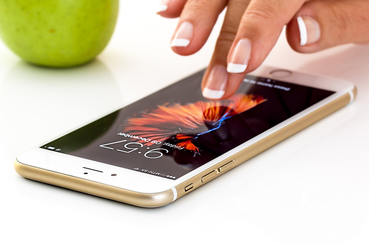 A woman's hand tentatively reaching out through the screen of her iPhone.